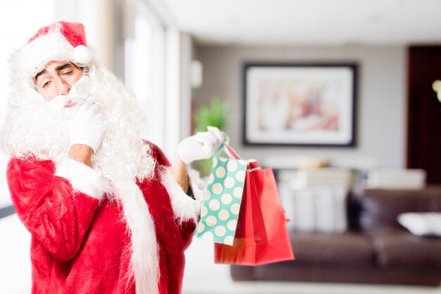 Papa noel mesándose la barba con bolsas de la compra