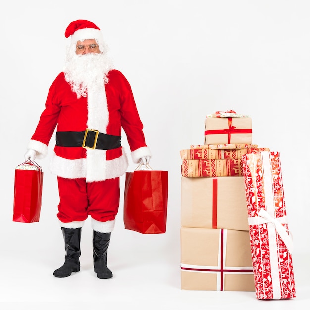 Papá Noel de pie y trayendo bolsas de regalo.