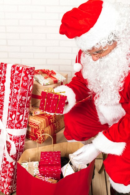Papá Noel poniendo cajas de regalo en saco grande