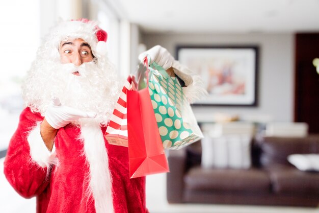 Papa noel señalando bolsas de la compra en una casa