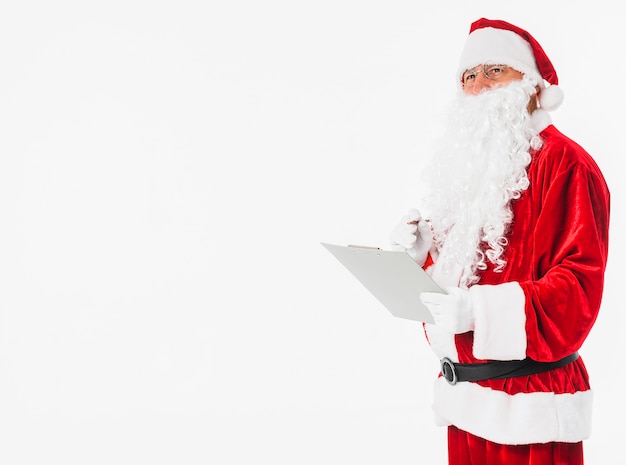 Papá Noel en sombrero rojo escribiendo en papel con lápiz