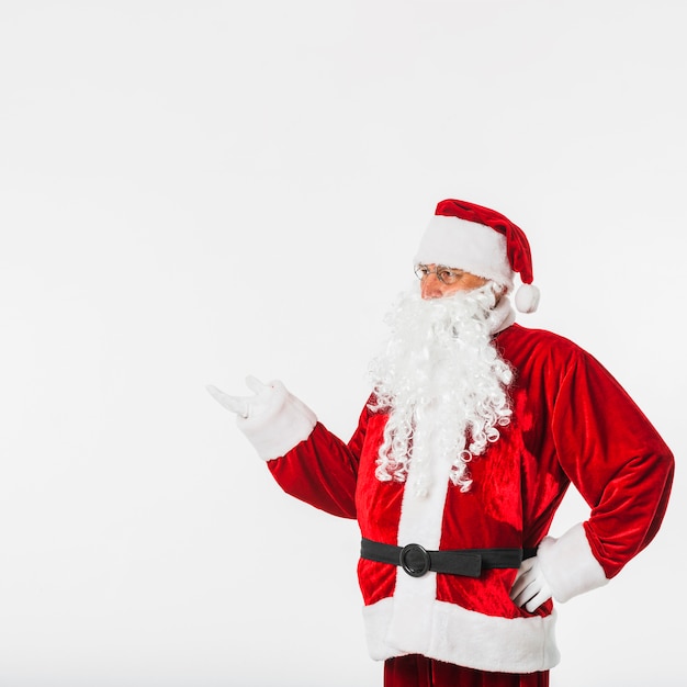 Papá Noel en el sombrero rojo que muestra algo con la mano