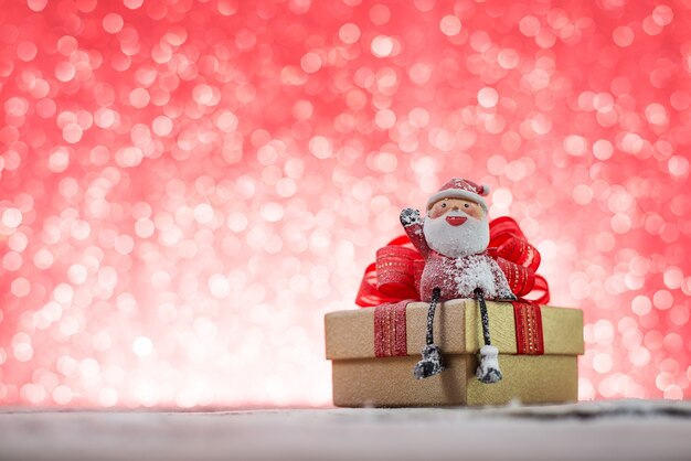 Papá noel sonriente sentado en un regalo de navidad