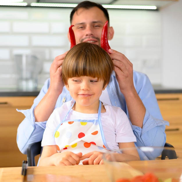 Foto gratuita papá pone pimientos kapia en la cabeza del niño