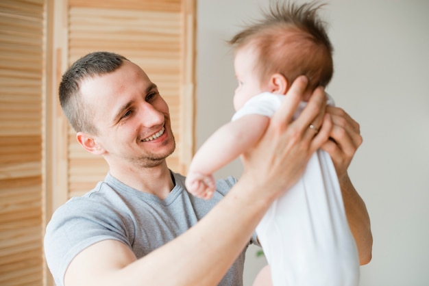 Papá sonriendo y sosteniendo bebe