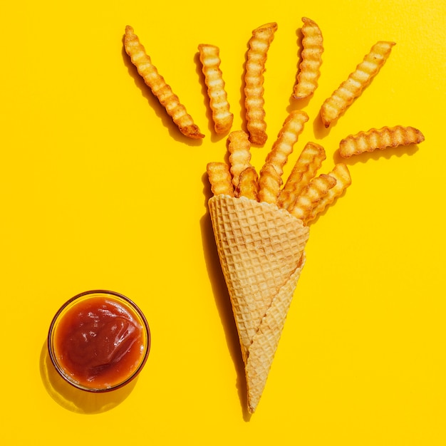 Papas fritas en un cono sobre fondo amarillo