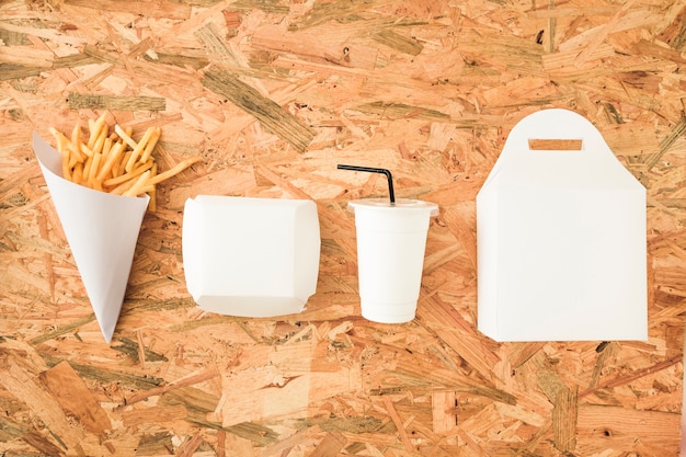 Papas fritas; Disposición de vasos y paquetes en fila en mesa de madera.