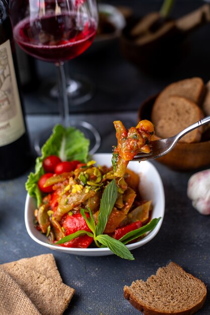 papas fritas junto con ensalada de vegetales frescos y vino tinto en escritorio gris