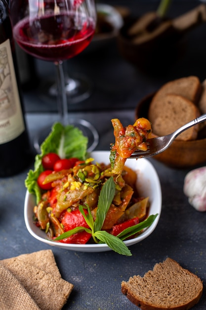 papas fritas junto con ensalada de vegetales frescos y vino tinto en escritorio gris