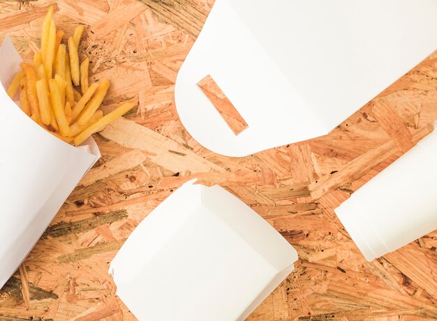 Papas fritas y maqueta de paquete blanco sobre fondo de madera