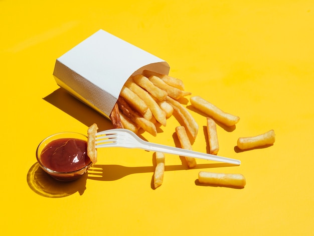 Papas fritas con salsa de tomate y tenedor de plástico