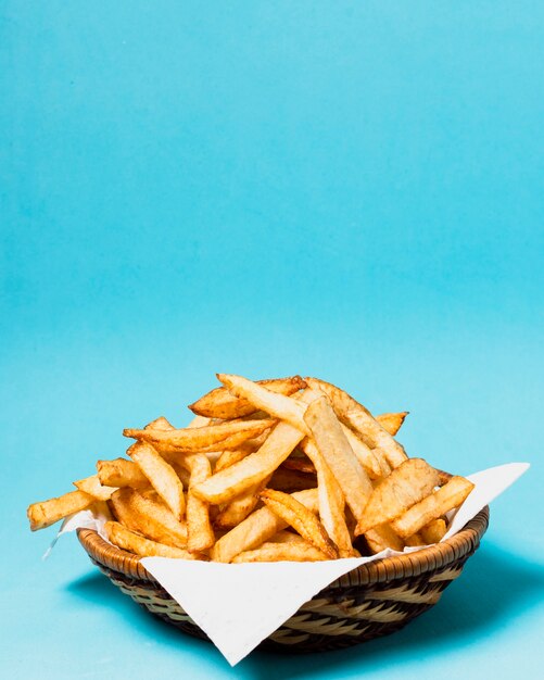 Papas fritas sobre fondo azul con espacio de copia