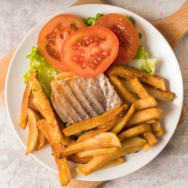 Papas fritas con tomates picados y carne.