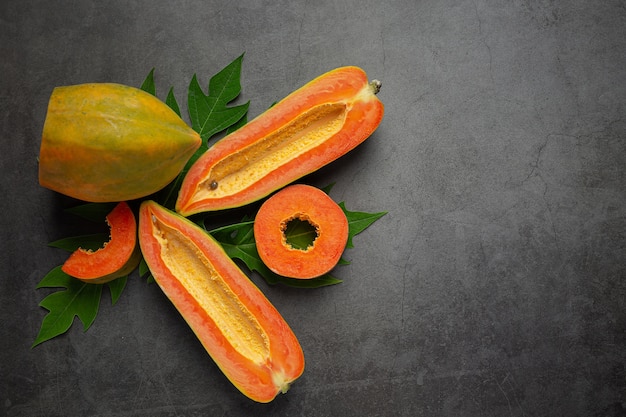 Papaya fresca, cortada por la mitad, colocada en un piso oscuro