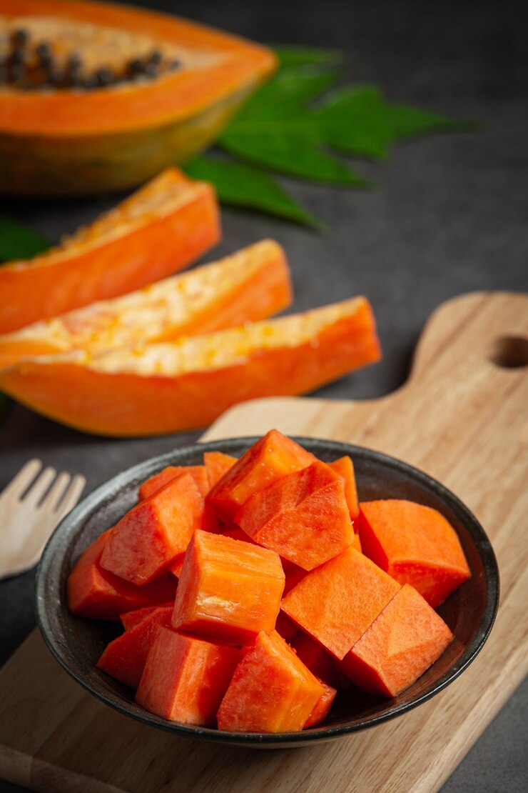 Foto gratuito papaya fresca, cortada en trozos, poner en un plato negro.