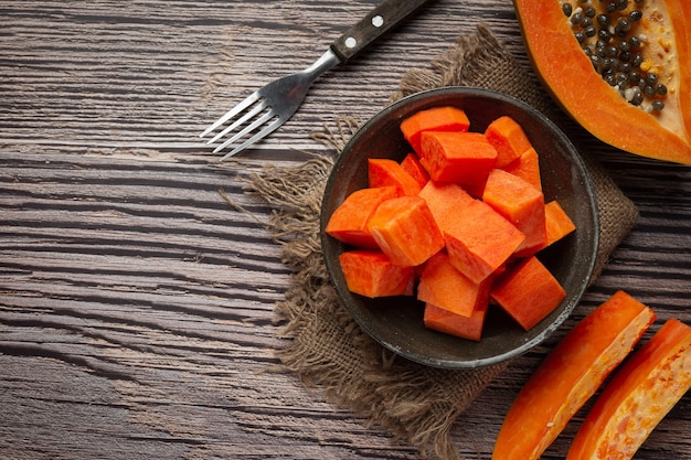 Papaya fresca, cortada en trozos, poner en un plato negro.