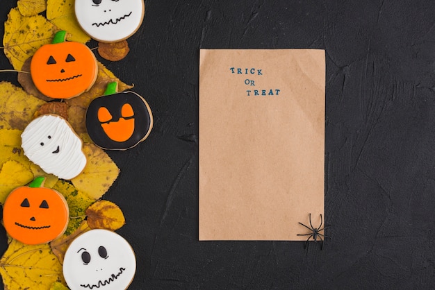 Foto gratuita papel artesanal con araña cerca de las galletas y hojas de halloween