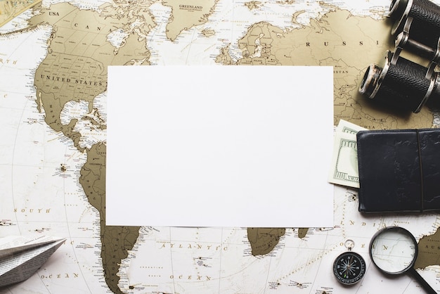 Papel en blanco con artículos de viaje y fondo de mapa del mundo