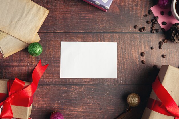 Un papel blanco en blanco y cajas de regalo sobre un piso de madera