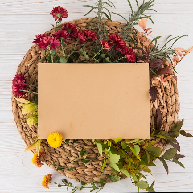 Foto gratuita papel en blanco con diferentes flores en la mesa