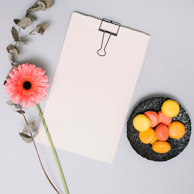 Papel en blanco con flores y galletas en la mesa