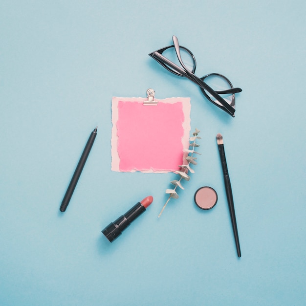 Papel en blanco con gafas y lápiz labial en la mesa