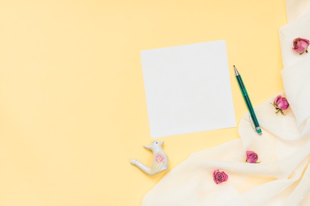 Foto gratuita papel en blanco con pequeñas rosas y pluma