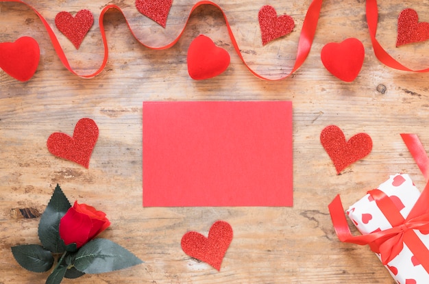 Papel en blanco con pequeños corazones en la mesa