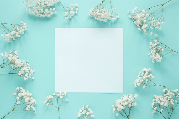 Papel en blanco con ramas de flores en la mesa