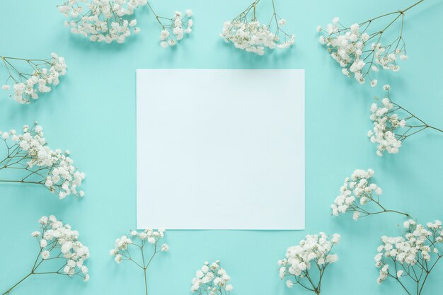 Papel en blanco con ramas de flores en la mesa