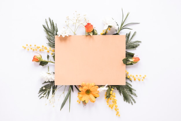 Papel en blanco sobre diferentes flores en la mesa