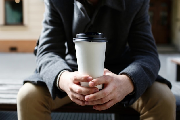 Papel blanco taza de café para llevar en brazos del hombre