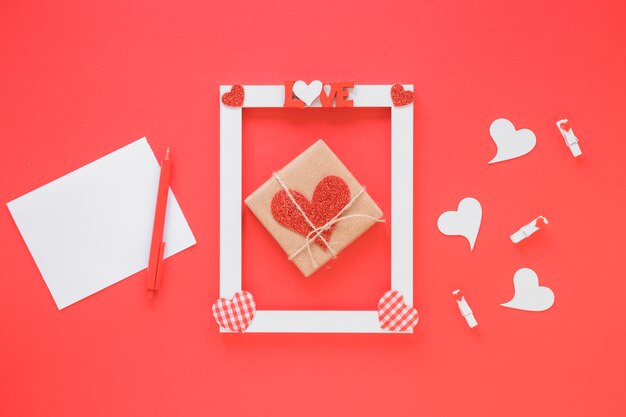 Papel cerca del marco con título de amor, presente y símbolos de corazón.