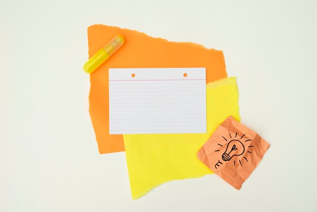 Papel de color y pegamento con bombilla dibujada a mano nota papel aislado sobre fondo blanco.