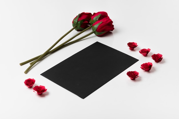 Foto gratuita papel negro con rosas en mesa