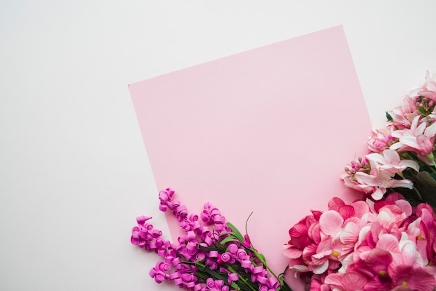 Papel rosado en blanco con flores de colores sobre fondo blanco