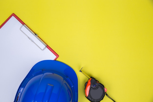 Foto gratuita papel vacío, cinta métrica y casco de trabajo.