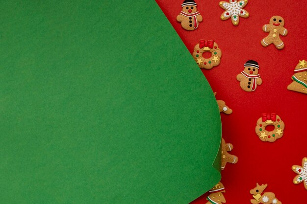 Foto gratuita papel verde y galletas de navidad en mesa roja