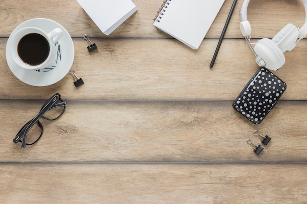 Papelería auriculares y taza de café en la mesa de madera