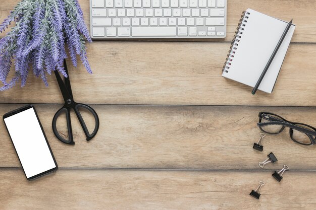 Papelería cerca de dispositivos electrónicos y flores de lavanda en el escritorio