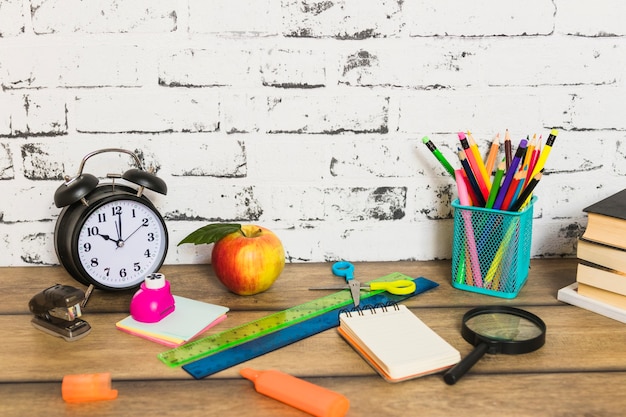 Foto gratuita papelería colorida y manzana colocada de forma aleatoria