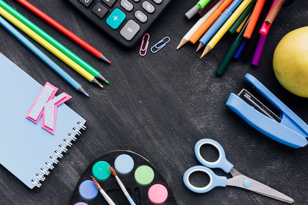 Papelería escolar colorido dispersos en pizarra