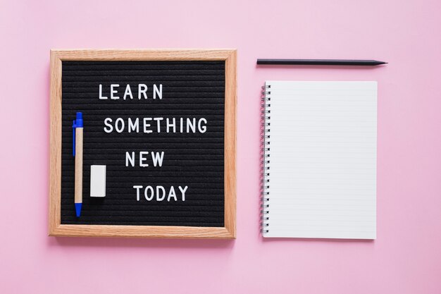 Papelerías con aprender algo nuevo hoy texto en pizarra sobre fondo rosa