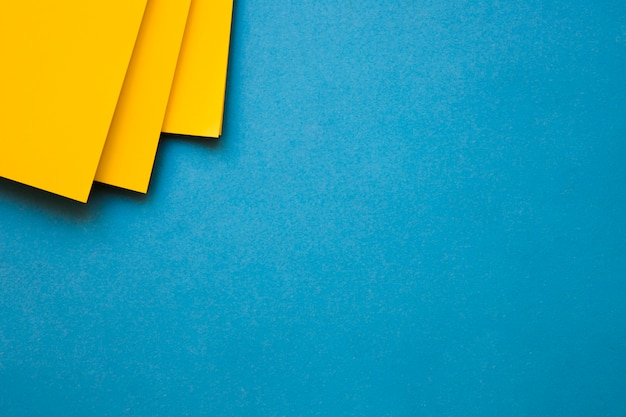 Papeles de cartón amarillo en la esquina del fondo azul