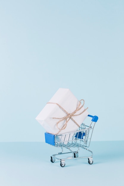 Foto gratuita paquete blanco en carrito de compras sobre fondo azul