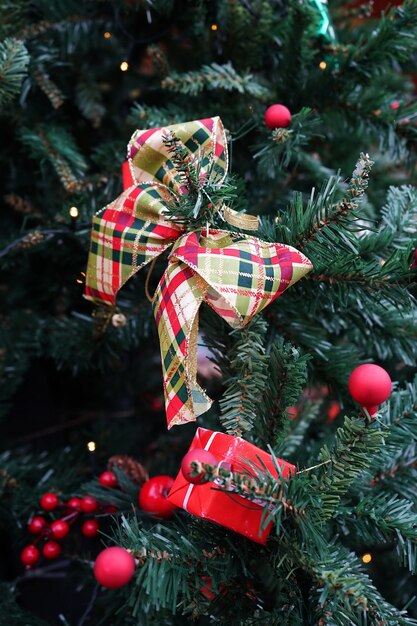 Paquete de decoración navideña, cinta y bolas rojas en el árbol de Navidad verde