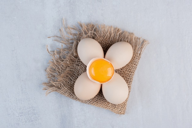 Paquete de huevos y yema de huevo en una cáscara sobre la mesa de mármol.