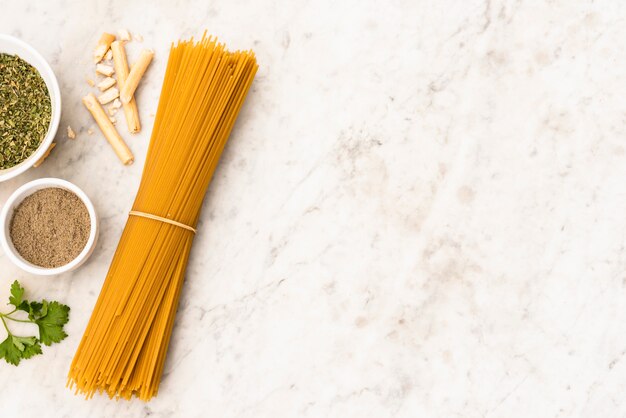 Paquete de pasta de espagueti sin cocer e ingrediente sobre fondo con textura de mármol