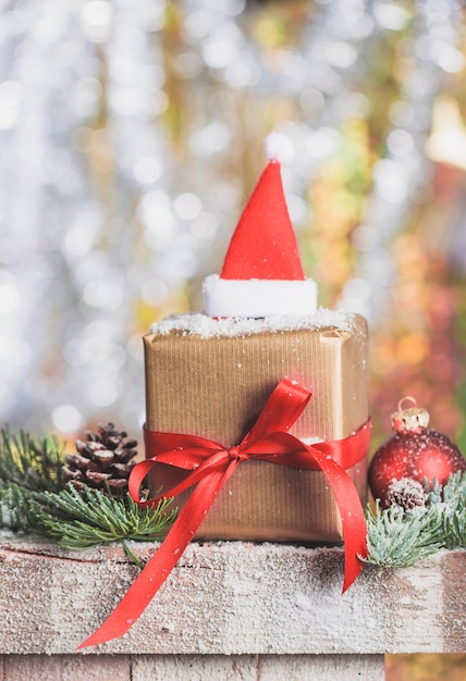 Paquete de regalo marrón con un lazo rojo y un sombrero de papa noel