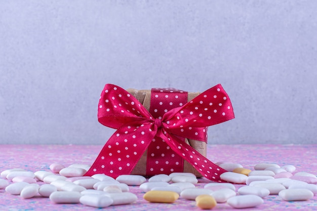 Foto gratuita paquete de regalo en medio de un paquete disperso de chicles sobre una superficie colorida